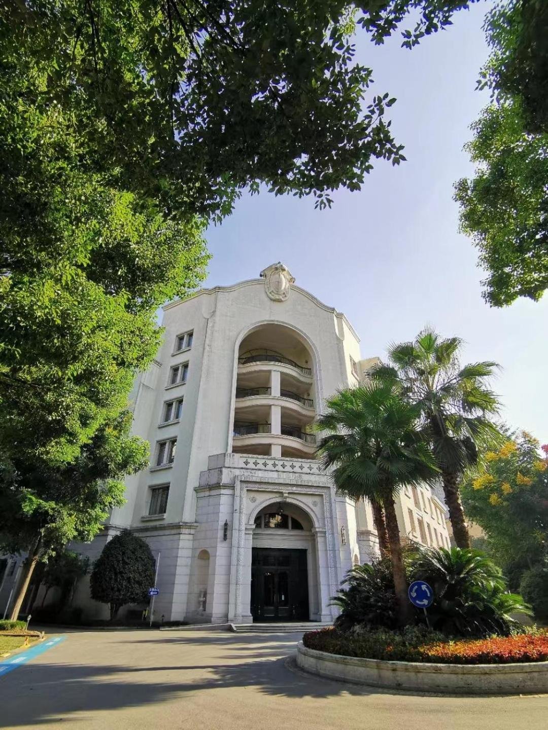A white Spanish-style hotel building framed by palm trees and green gardens